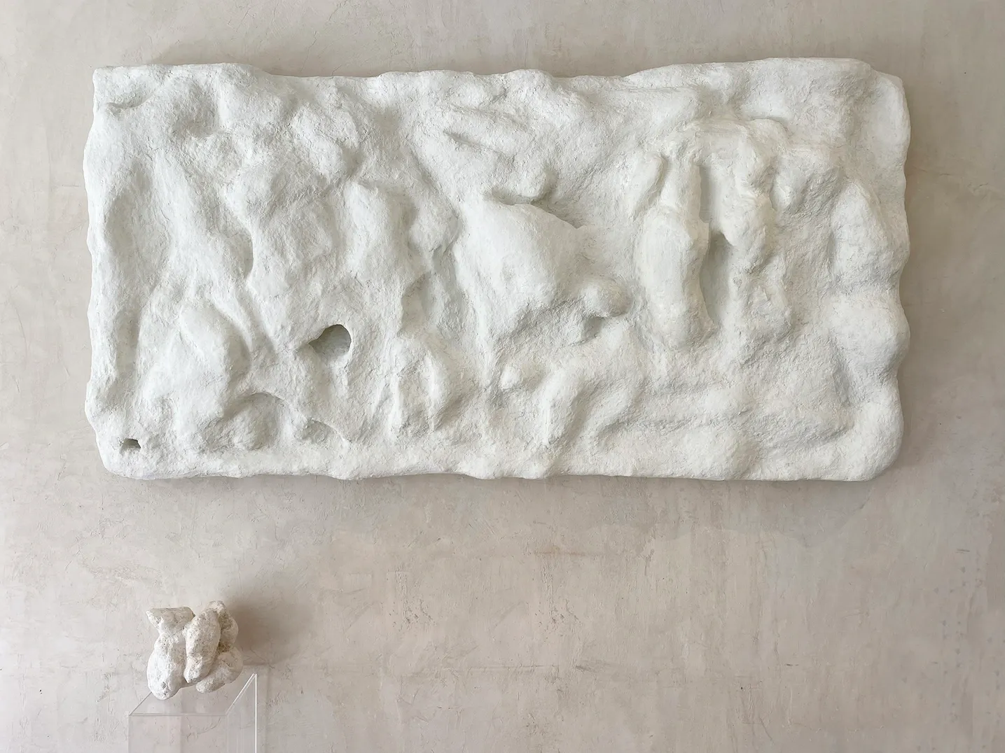 Painel branco em relevo, longo, sobre parede de massa